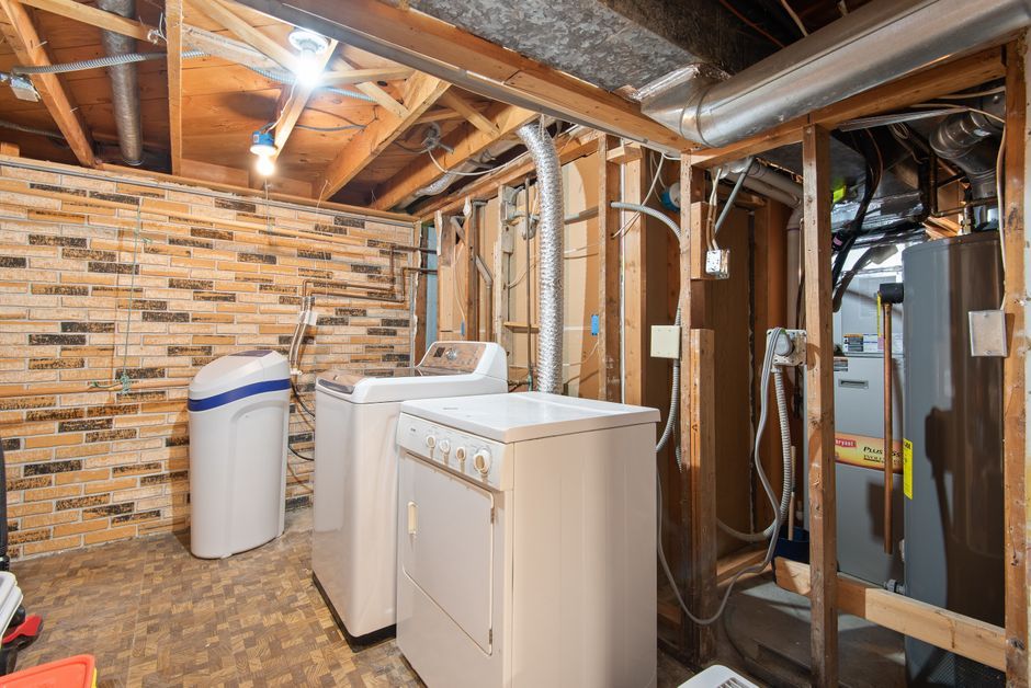 water heater in a modern home utility room with hot water pipes and daily household chores in background
